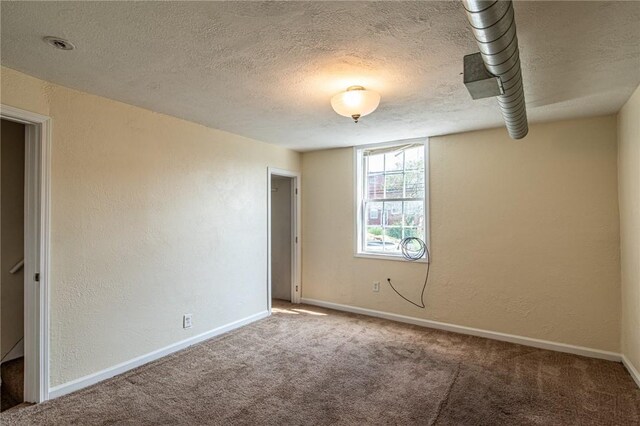 carpeted empty room with a textured ceiling