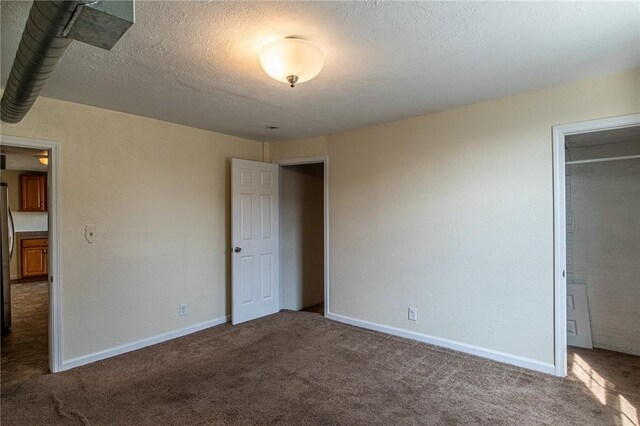 unfurnished bedroom featuring a textured ceiling and carpet