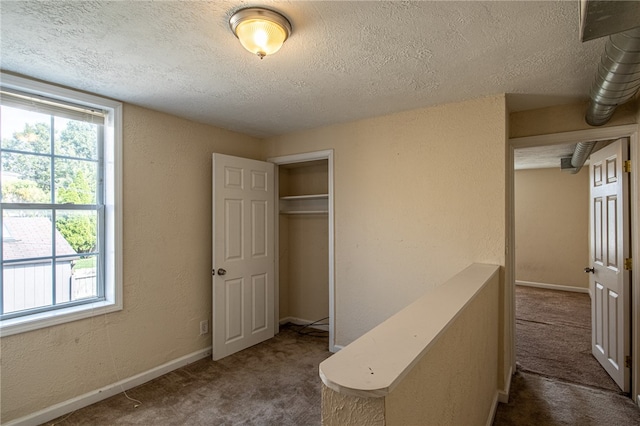 unfurnished bedroom with a textured ceiling, dark colored carpet, and a closet