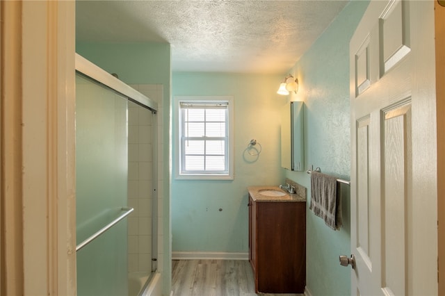 bathroom with a textured ceiling, vanity, a shower with shower door, and wood-type flooring