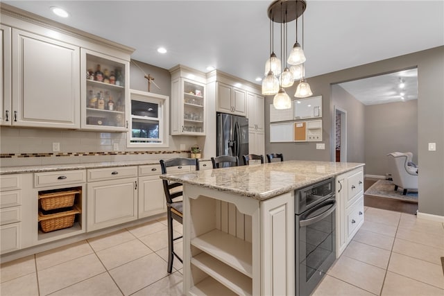 kitchen featuring decorative backsplash, a breakfast bar area, stainless steel appliances, a center island, and light tile patterned floors