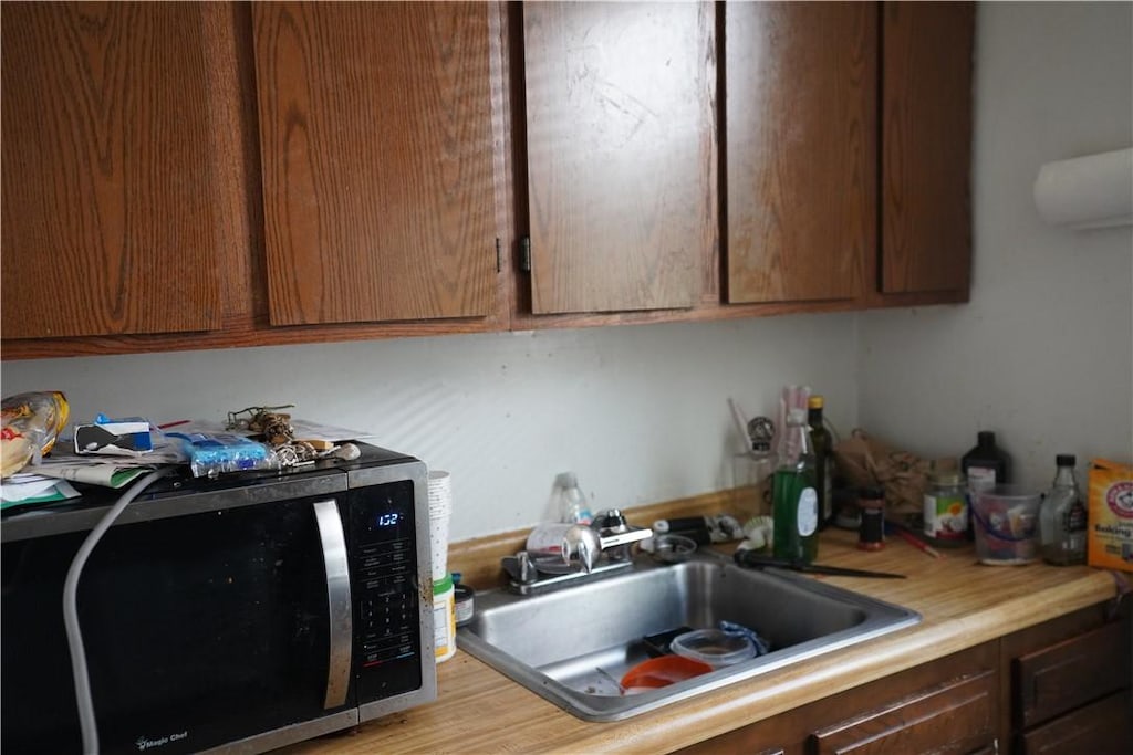 kitchen featuring a sink, light countertops, and stainless steel microwave