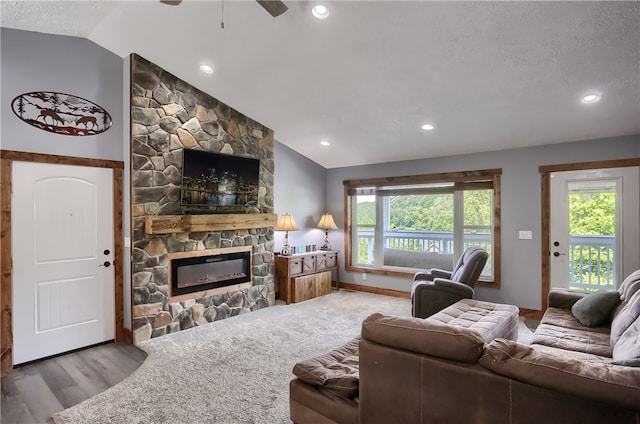 living room with a textured ceiling, a fireplace, hardwood / wood-style flooring, lofted ceiling, and ceiling fan