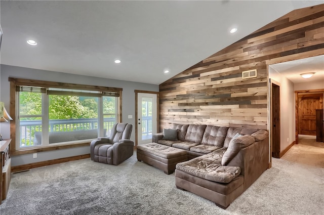 carpeted living room featuring vaulted ceiling, a healthy amount of sunlight, and wood walls