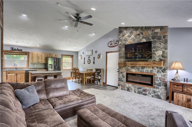 living room featuring a stone fireplace, ceiling fan, lofted ceiling, and a healthy amount of sunlight