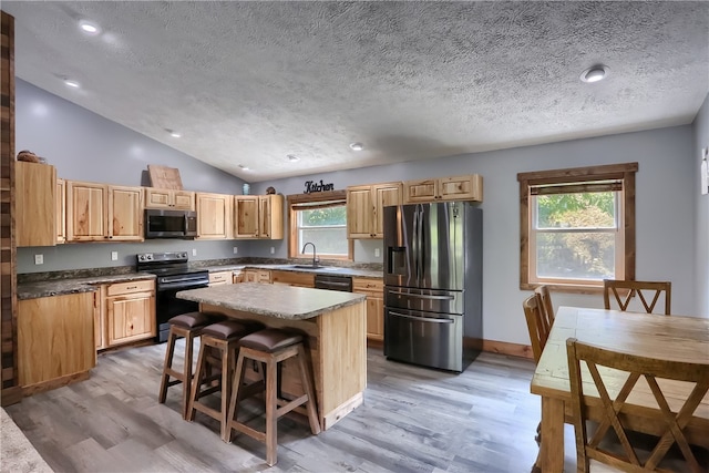 kitchen with a center island, light hardwood / wood-style flooring, appliances with stainless steel finishes, sink, and lofted ceiling