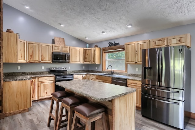 kitchen featuring a center island, vaulted ceiling, light hardwood / wood-style flooring, and appliances with stainless steel finishes