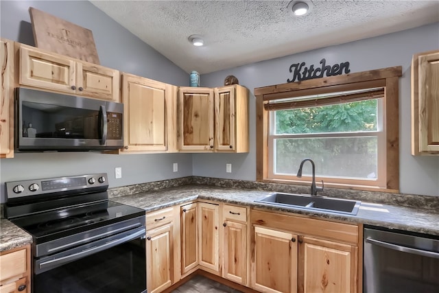 kitchen featuring a textured ceiling, vaulted ceiling, sink, and appliances with stainless steel finishes