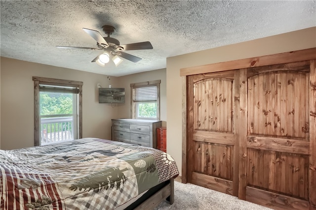 bedroom with ceiling fan, carpet, and a textured ceiling