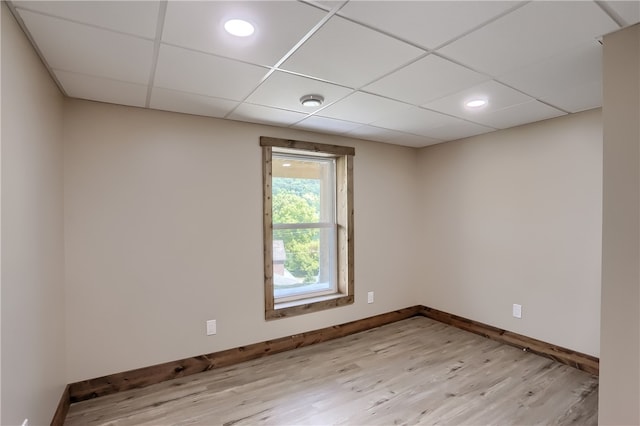 spare room featuring light hardwood / wood-style flooring and a drop ceiling