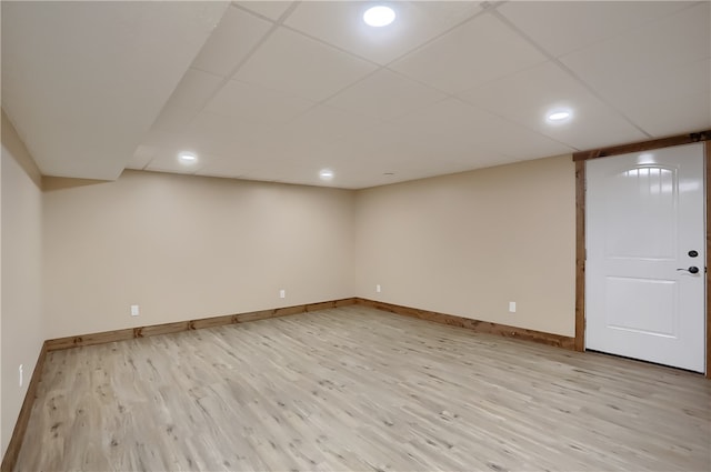 basement featuring light wood-type flooring and a drop ceiling