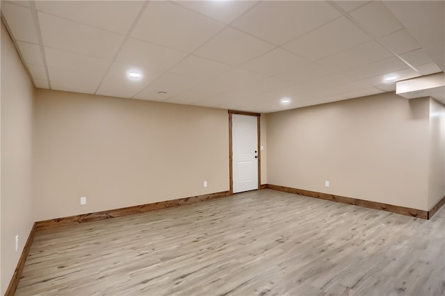 basement featuring light wood-type flooring and a drop ceiling