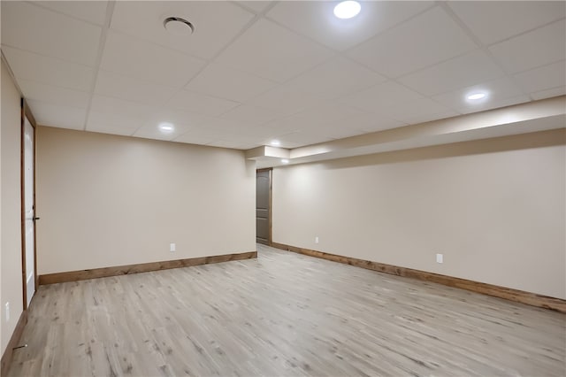 basement with a drop ceiling and light hardwood / wood-style floors