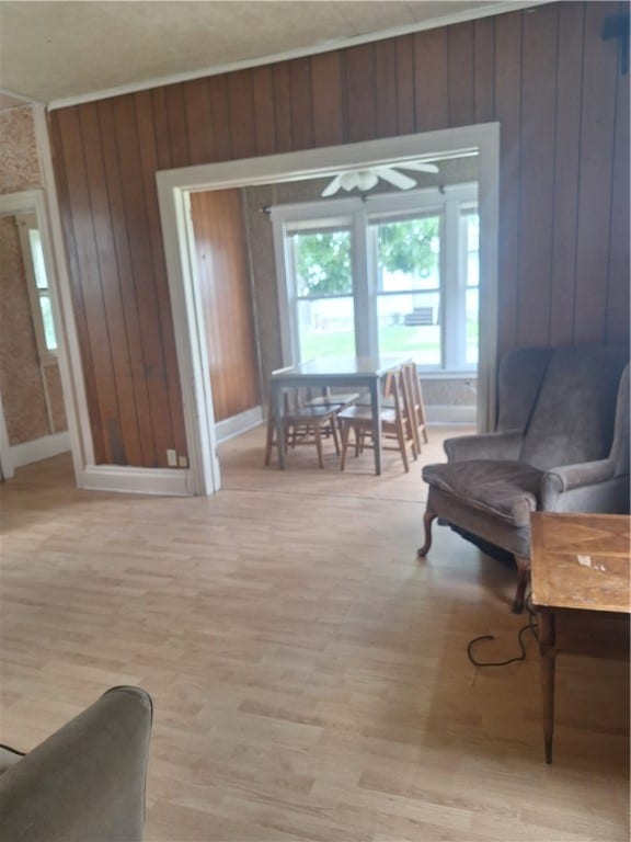 sitting room with light hardwood / wood-style flooring, ceiling fan, and wooden walls