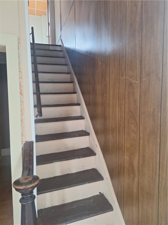 stairway featuring wood walls