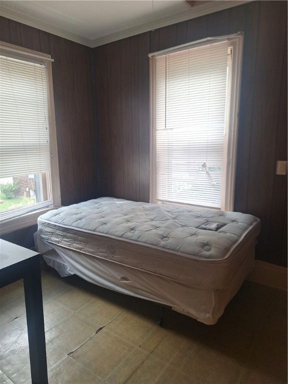 bedroom featuring crown molding and wooden walls