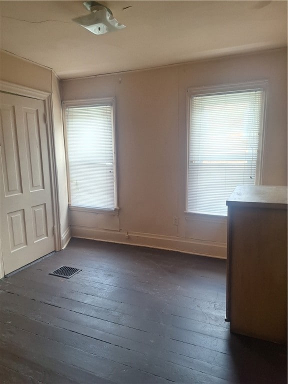 unfurnished bedroom featuring dark wood-type flooring and multiple windows