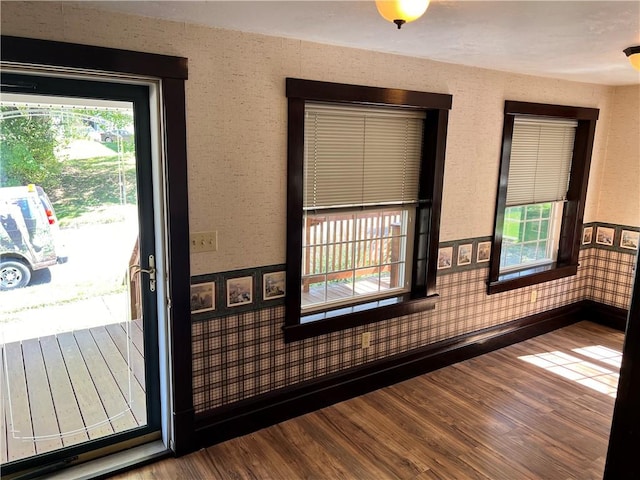 interior space with baseboards, wood finished floors, and wallpapered walls