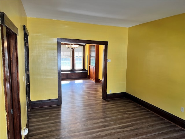 unfurnished room featuring a notable chandelier and dark hardwood / wood-style floors