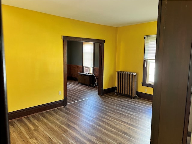 spare room featuring dark wood-type flooring and radiator heating unit