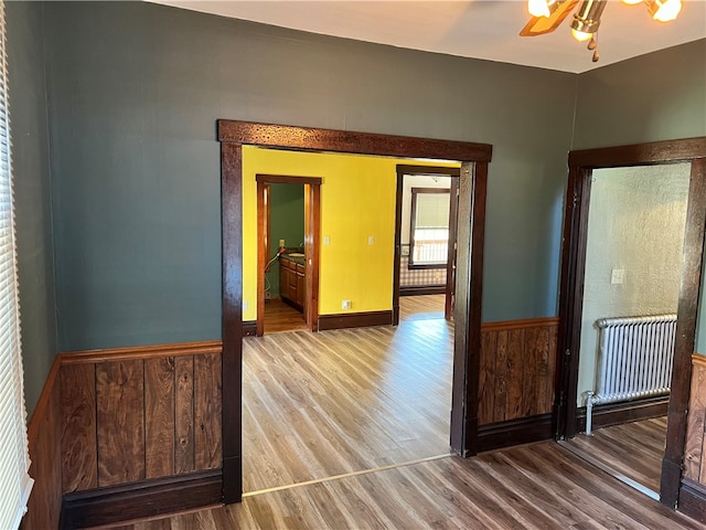 corridor featuring radiator, wooden walls, and hardwood / wood-style flooring