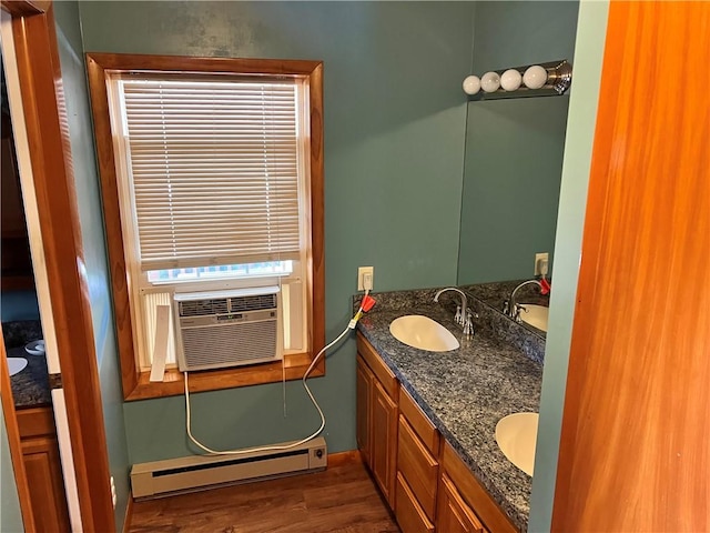 bathroom with a baseboard heating unit, double vanity, a sink, and wood finished floors