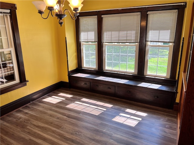 empty room with an inviting chandelier and dark hardwood / wood-style flooring