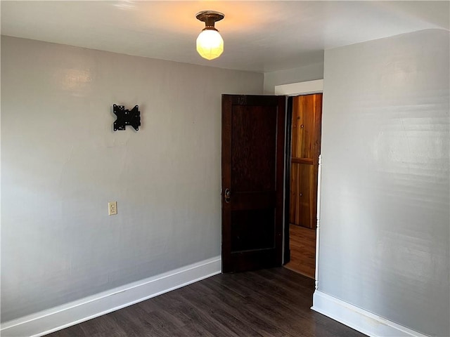 unfurnished room featuring dark wood-style flooring and baseboards