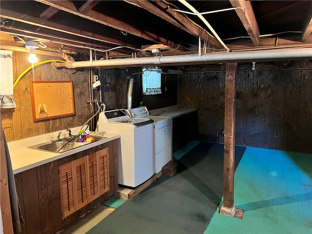 basement with wooden walls, washer and clothes dryer, and sink