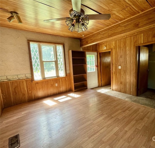 empty room with wooden ceiling, hardwood / wood-style flooring, wood walls, and ceiling fan