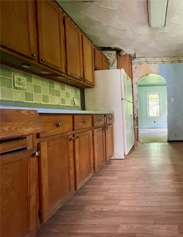 kitchen featuring decorative backsplash, white fridge, and light hardwood / wood-style floors