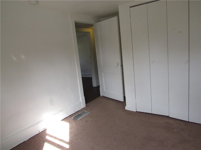 unfurnished bedroom featuring dark carpet and a closet