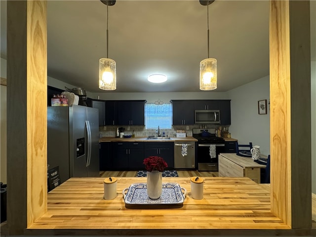 kitchen with decorative light fixtures, stainless steel appliances, tasteful backsplash, and sink