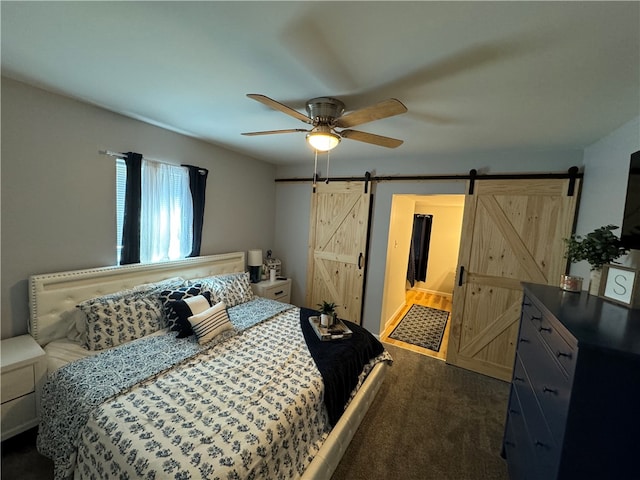 carpeted bedroom with ceiling fan, a barn door, and ensuite bathroom