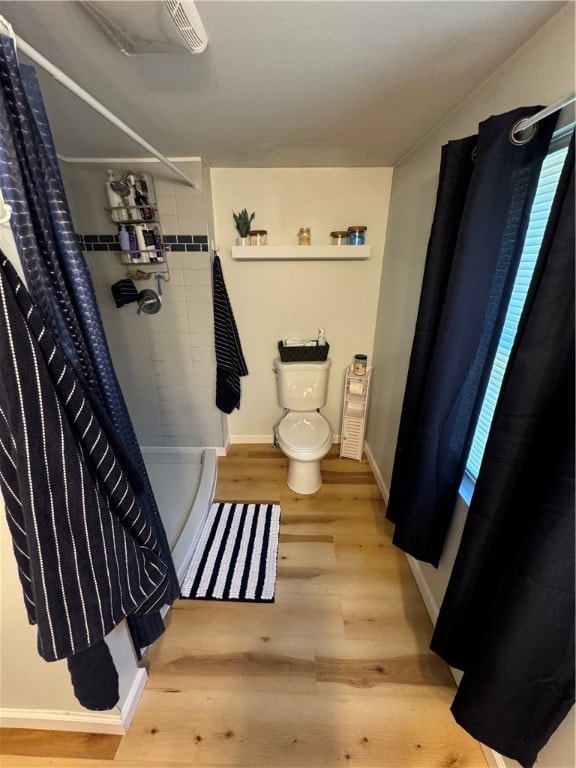 bathroom with a shower with curtain, wood-type flooring, and toilet