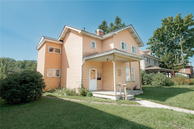 rear view of house with a lawn and a porch