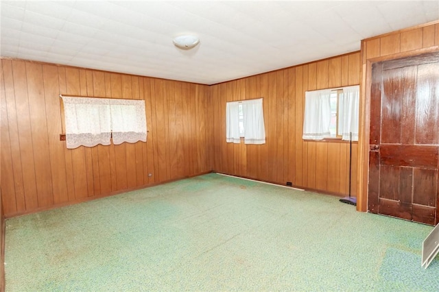 carpeted spare room featuring wooden walls