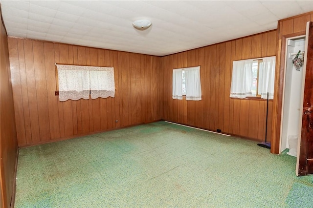 carpeted empty room featuring wooden walls