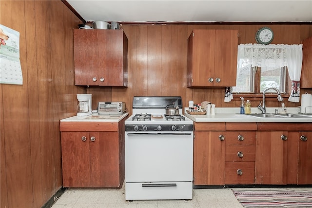 kitchen featuring wooden walls, sink, and white range with gas cooktop