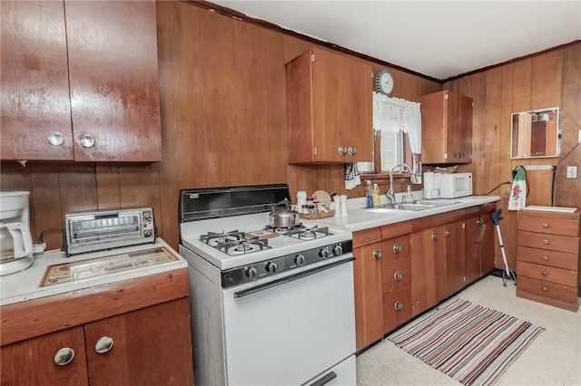 kitchen featuring wood walls, white appliances, and sink