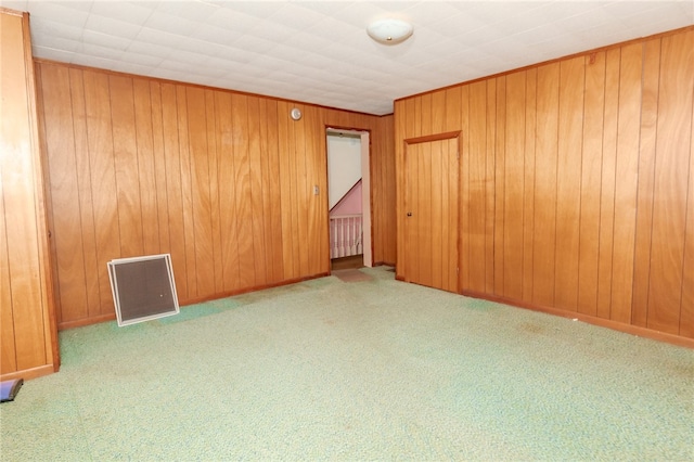 unfurnished room with wood walls and light carpet