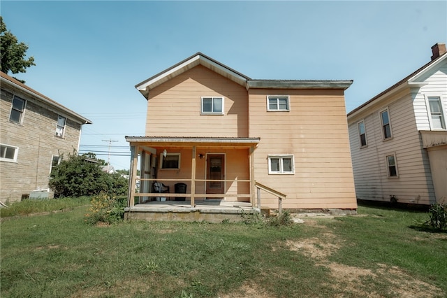 back of house featuring covered porch and a yard