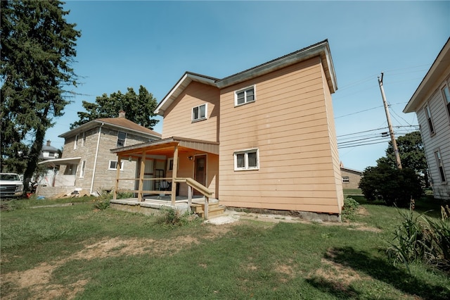 rear view of property featuring a porch and a yard