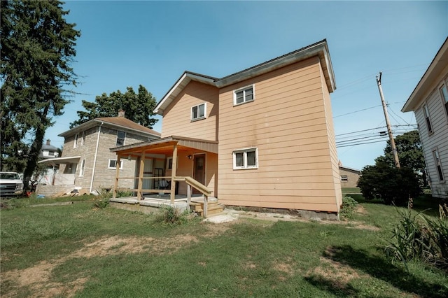 rear view of house featuring a lawn and a porch