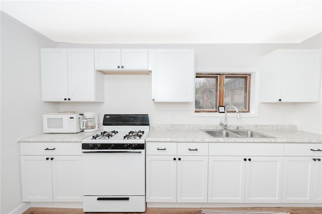 kitchen with a sink, white cabinets, white appliances, and light stone countertops