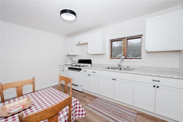 kitchen with white cabinets, light stone counters, a sink, light wood finished floors, and white appliances