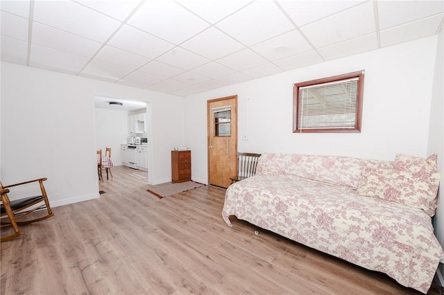 living room featuring baseboards, a paneled ceiling, and wood finished floors