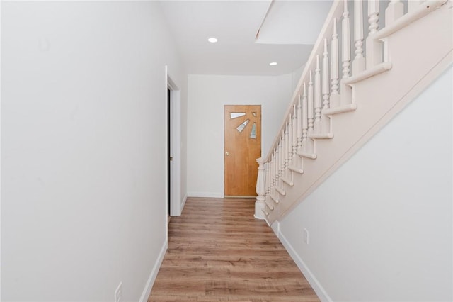 corridor featuring baseboards, recessed lighting, light wood-style floors, and stairway