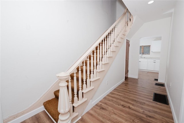 stairs with baseboards, wood finished floors, and visible vents
