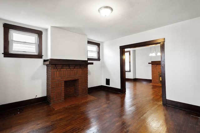 unfurnished living room featuring a brick fireplace and dark hardwood / wood-style floors